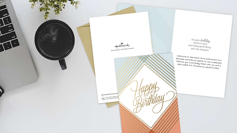 Personalized happy birthday card for team member on desk with computer and cup of coffee