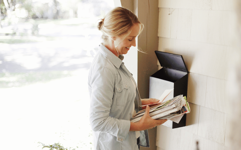 Female Getting Stack of Mail at Home Mailbox