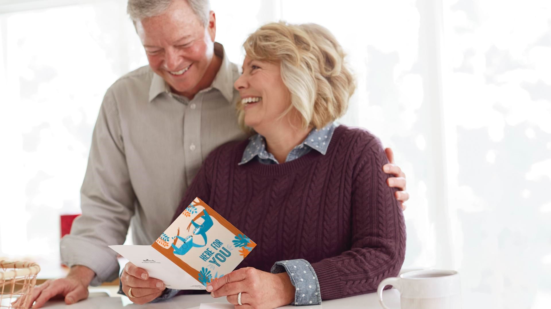 Older couple smiling and holding health plan card