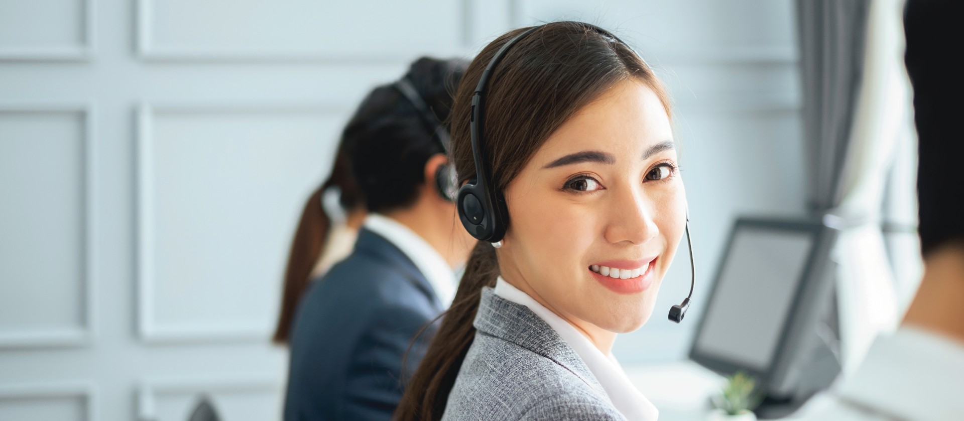 Call Center Rep with Headphones Smiling at the Camera