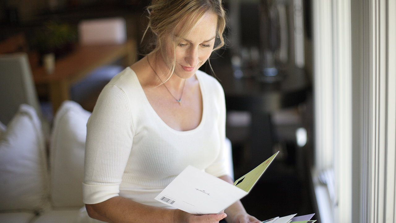 Female reading card from mail at home