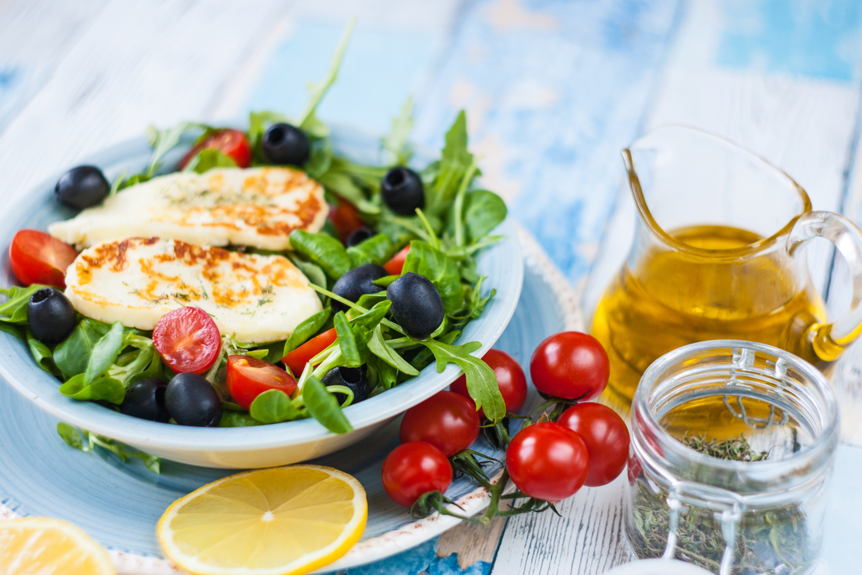 Sallad med grillad halloumi på blått fat med citron och tomater på sidan - shutterstock 1031023330