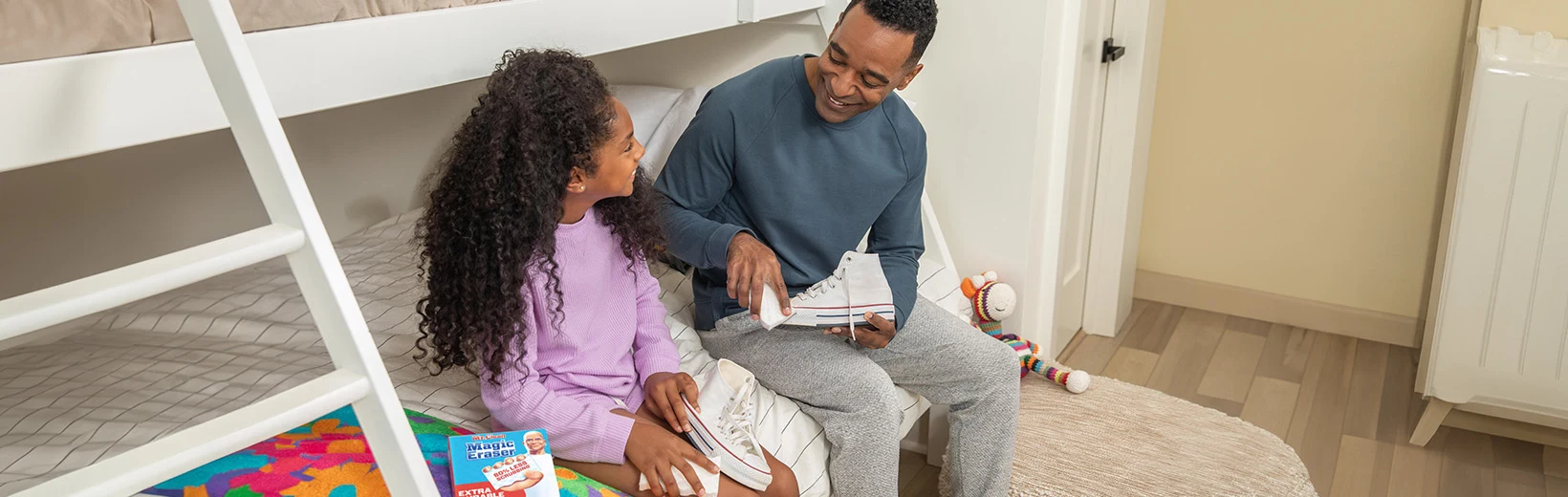 Father and daughter clean sneakers sitting on bed