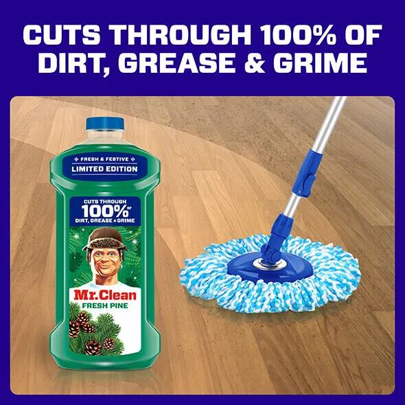 Mr Clean Fresh Pine cleaner bottle next to a mop on a wooden floor, highlighting its effectiveness against dirt and grime