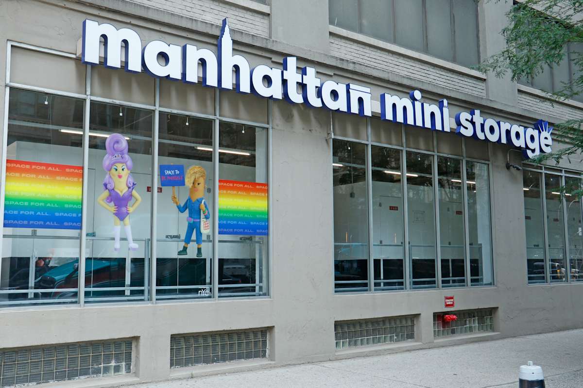 A street view of Manhattan Mini Storage with colorful art supporting NYC pride displayed in the windows