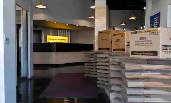 Manhattan Mini Storage - Brooklyn self storage facility office with moving boxes and the front desk with a lighted logo sign