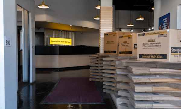 Manhattan Mini Storage - Brooklyn self storage facility office with moving boxes and the front desk with a lighted logo sign