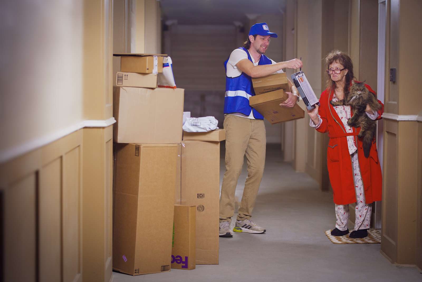 A lady in a bathrobe signs for a large stack of packages