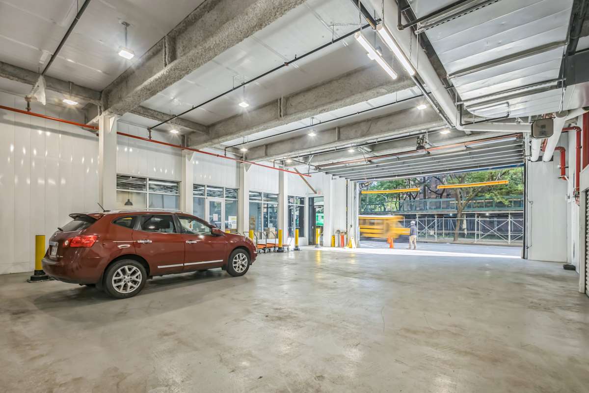 Clean, well-lit indoor loading bay with high ceilings, yellow safety bollards, a parked SUV, and rolling carts near storage unit entrances