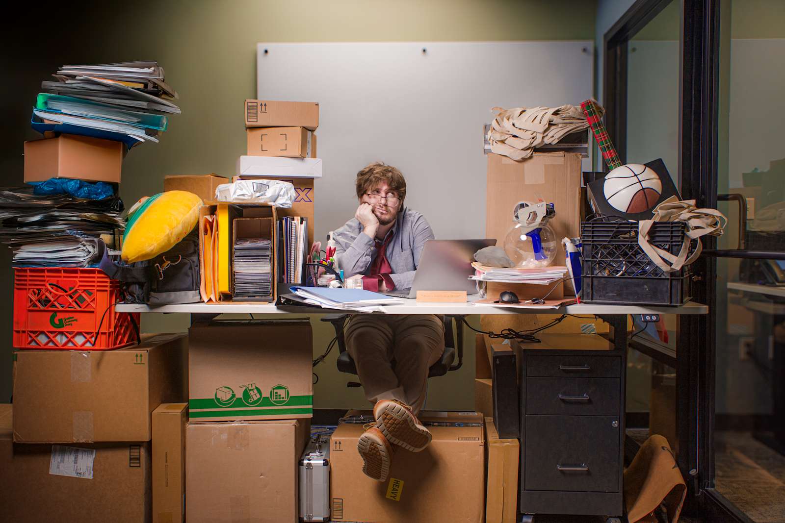 A crowded desk with stacks of boxes and clutter overwhelming a office