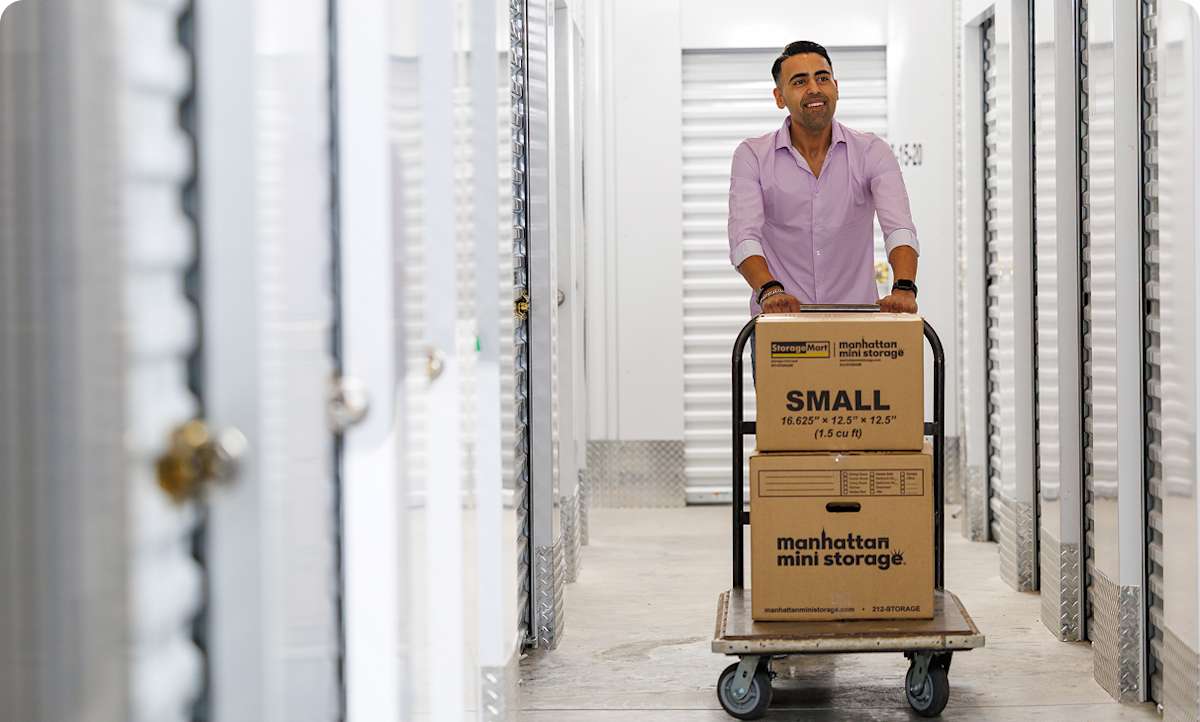 A woman sits on the couch on her phone with Manhattan Mini Storage moving boxes around her
