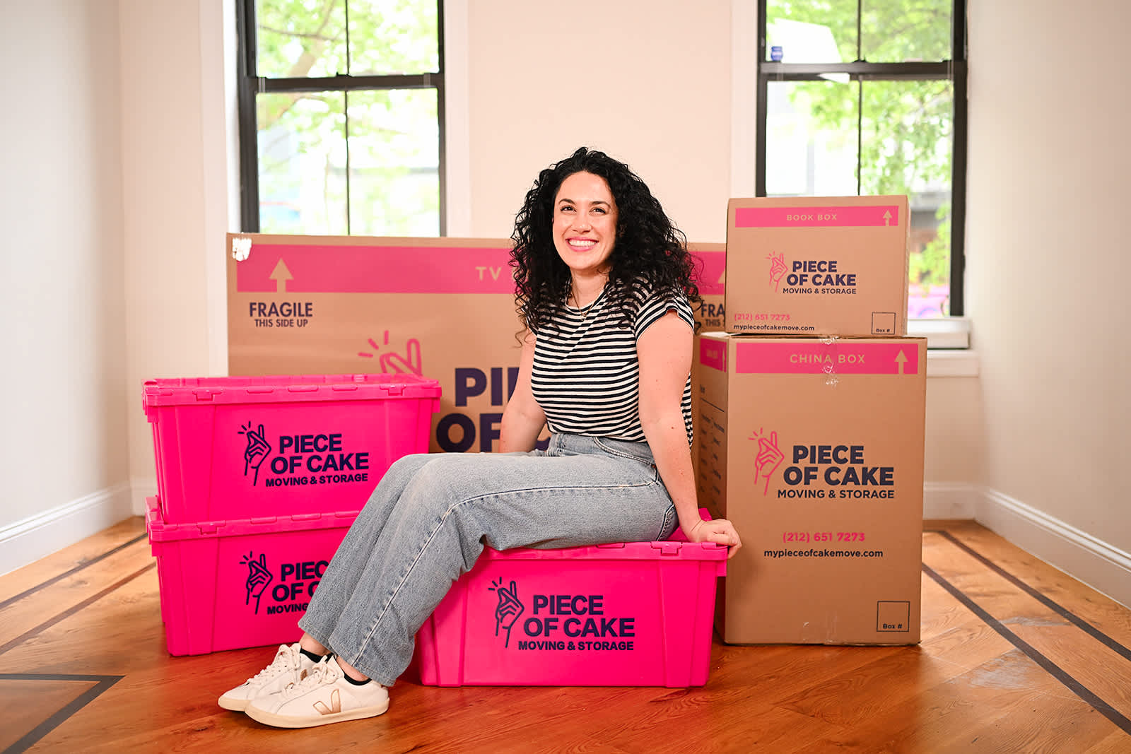 smiling customer surrounded by Piece of Cake moving boxes 