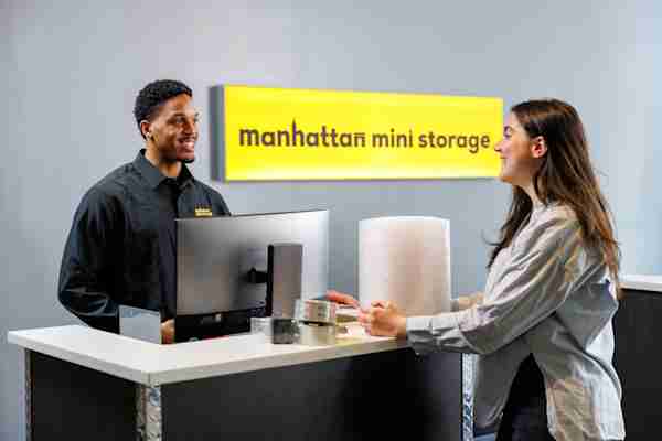 Friendly Manhattan Mini Storage employee helping a customer at the front desk.