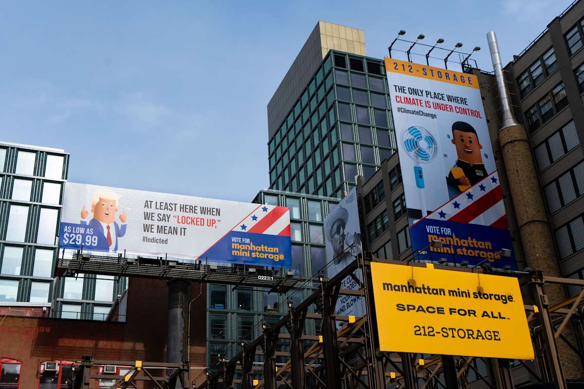 Billboards for Manhattan Mini Storage at 260 Spring Street, New York City, featuring humorous ads about storage, climate control, and affordable pricing, are displayed on the exterior of a modern urban building.