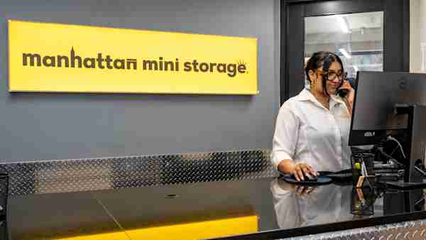 Employee helping a customer over the phone at the front desk of Manhattan Mini Storage on 28 2nd Ave