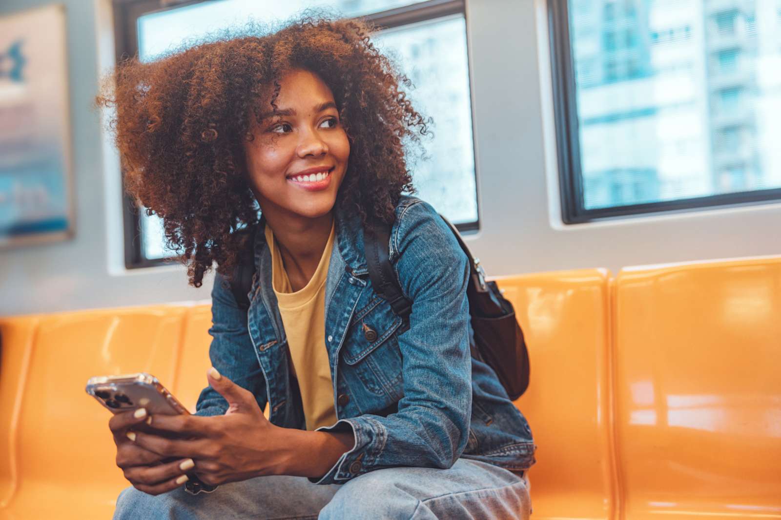 A young girl smiles looking off camera while holding a cell phone