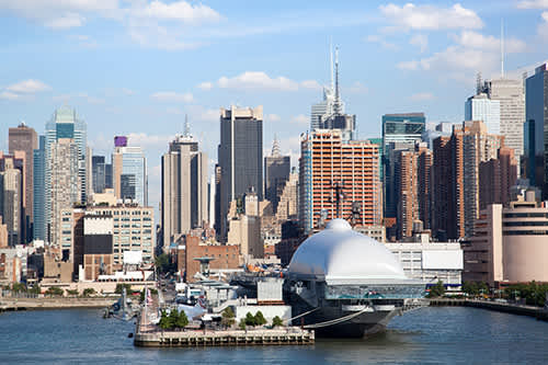 View of Manhattan skyline behind the Intrepid Sea, Air & Space Museum on the Hudson River.