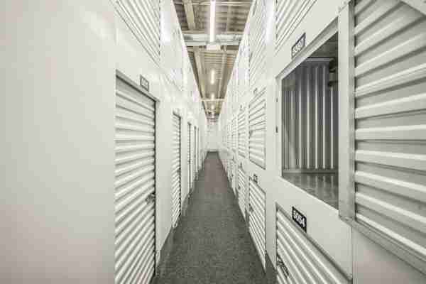 a well-lit hallway at Manhattan Mini Storage with storage lockers and medium size storage units