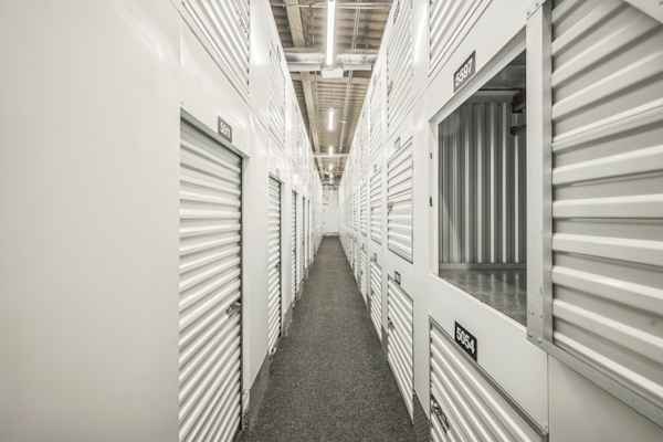 a well-lit hallway at Manhattan Mini Storage with storage lockers and medium size storage units