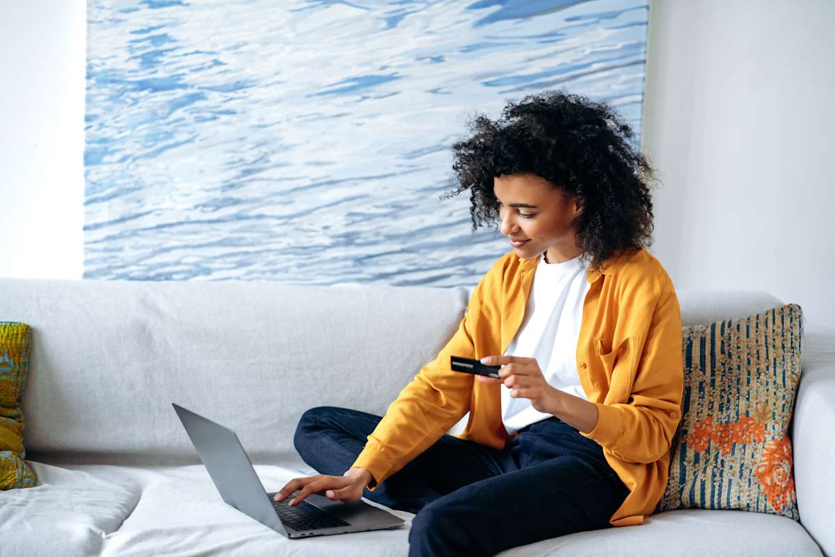 a woman sits on the couch online shopping from her laptop