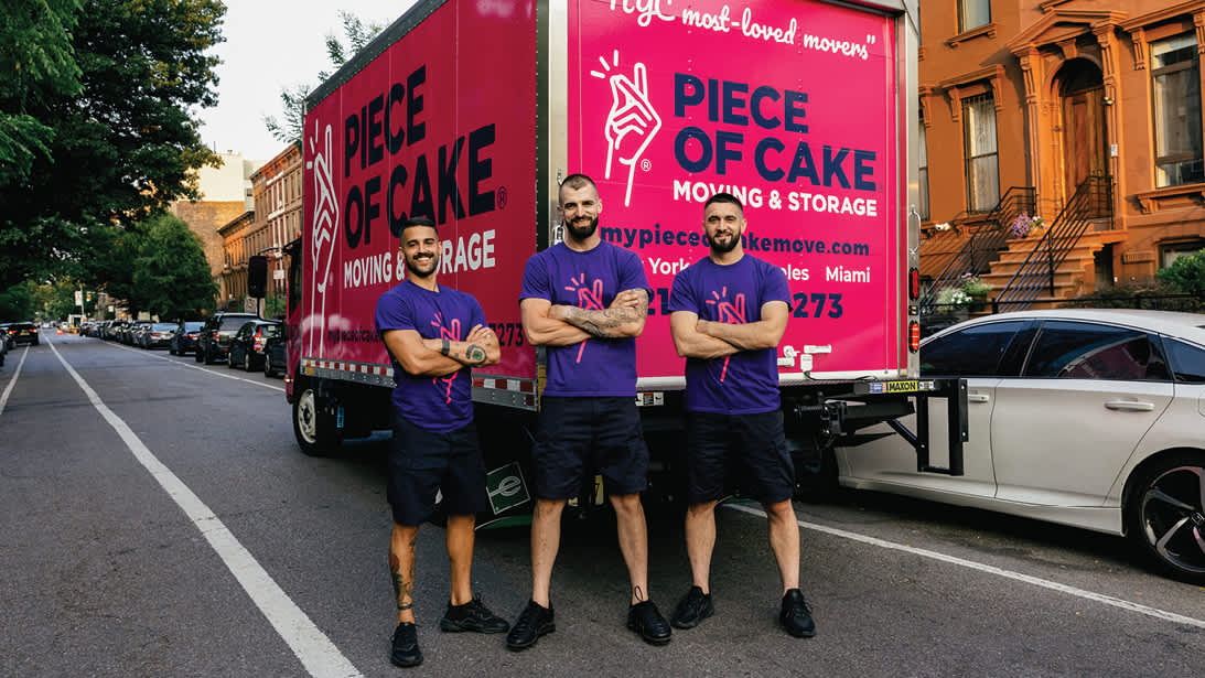 Moving team standning in front of a pink Piece of Cake moving truck