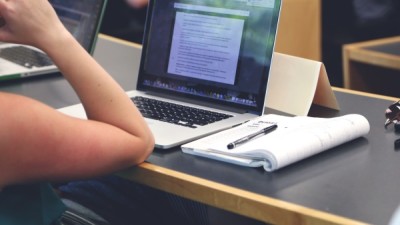 Student working on laptop with notebook open