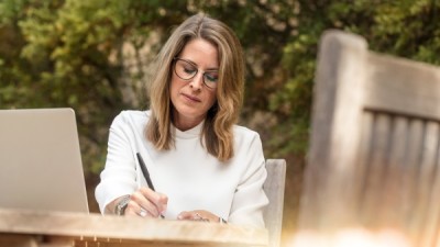 Woman writes outside with computer