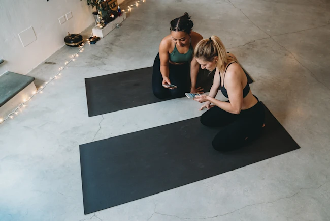 Two women looking at their smartphones after the yoga class