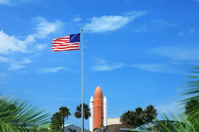 Waving American flag at Kennedy space center entrance with space rocket
