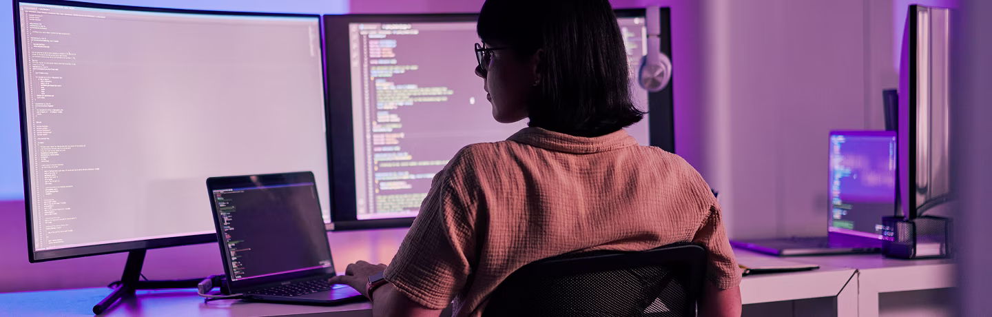 Woman typing on computer keyboard in the dark against colorful background