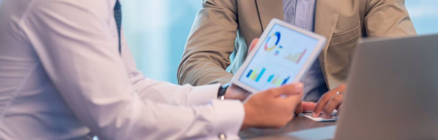 Business people working on financial data, graphs, and charts on a digital tablet.