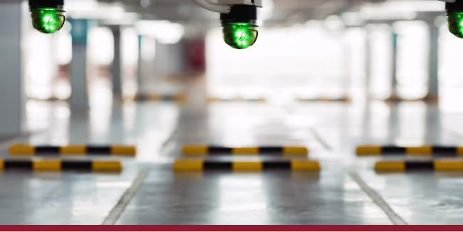 Close up of green parking availability sensor light indicating an empty parking spot in an indoor garage with blurred background and space markers.