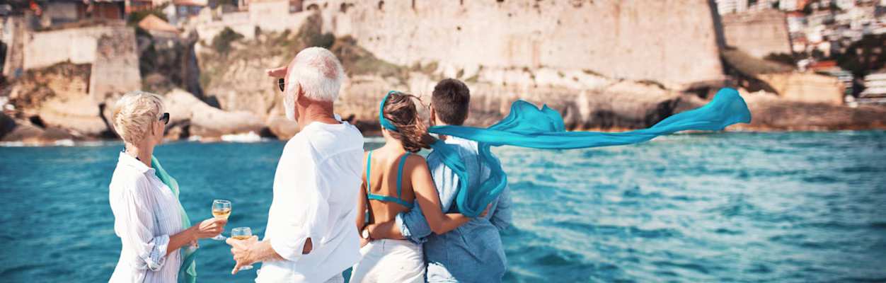 Senior couple on a sailing cruise looking at coastline.