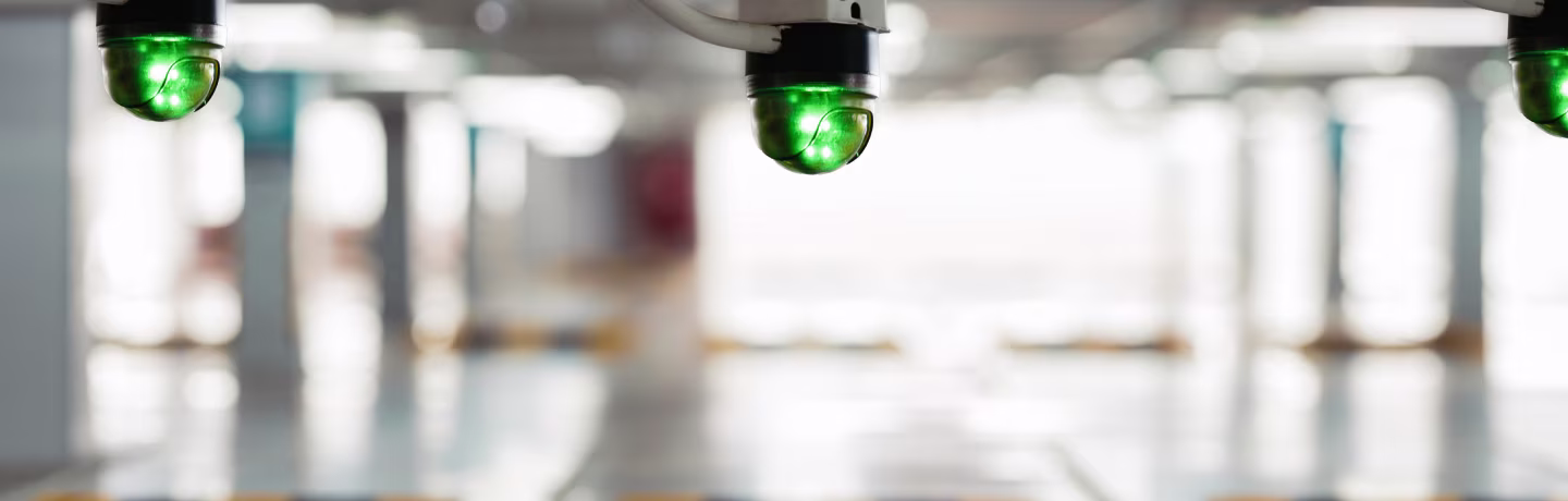 Close up of green parking availability sensor light indicating an empty parking spot in an indoor garage with blurred background and space markers.