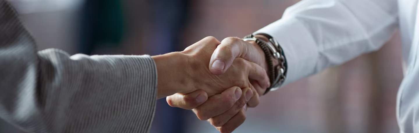 Image of two businesspeople who handshake at the start of a partnership.