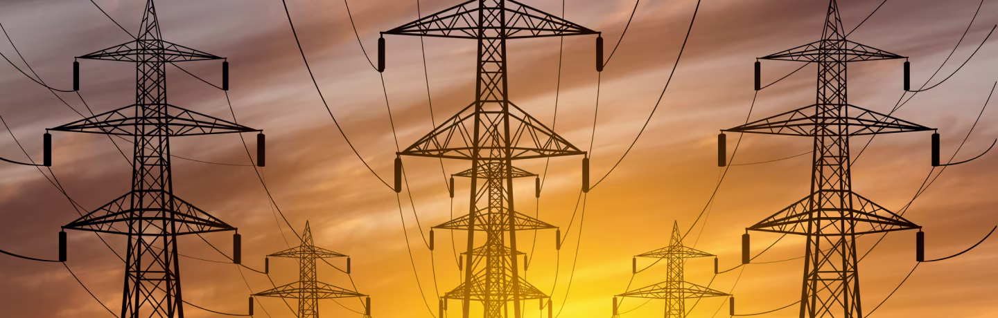 High voltage towers with sunset background; power lines against the sky