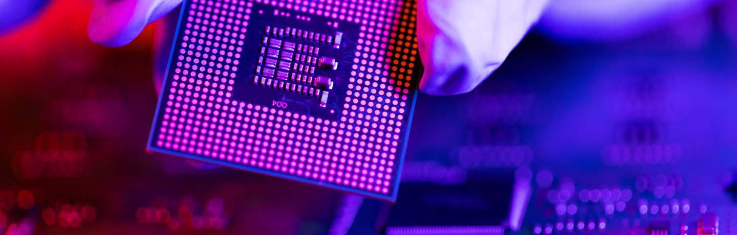 The engineer's gloved hand is holding the CPU chip against the background of the motherboard.