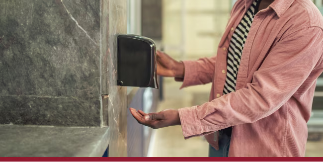 An African American man uses hand sanitizer while waiting for a bus at a station.