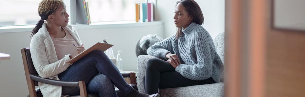 A therapist meets with her female client in her office.