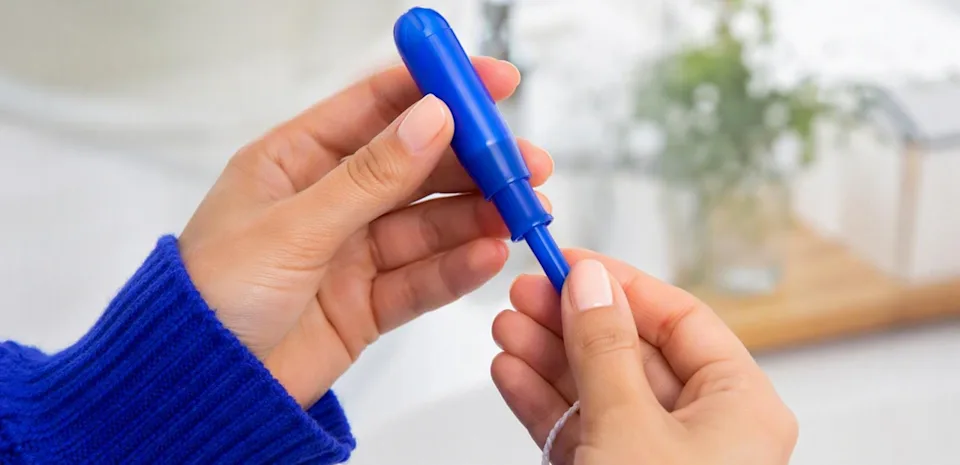 Applicator tampon in hands showing the grip, pusher, and string that make insertion easy for beginners