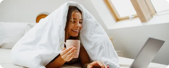Woman with her laptop, browsing Tampax FAQs on absorbency, safety and tampon use