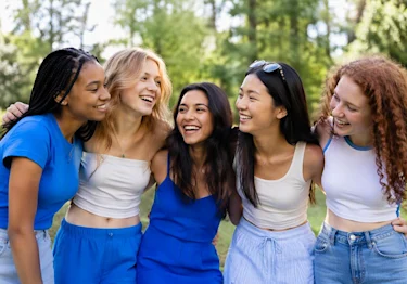 Diverse group of smiling teen girls outdoors, reflecting that there is no set age to feel ready for tampax tampons