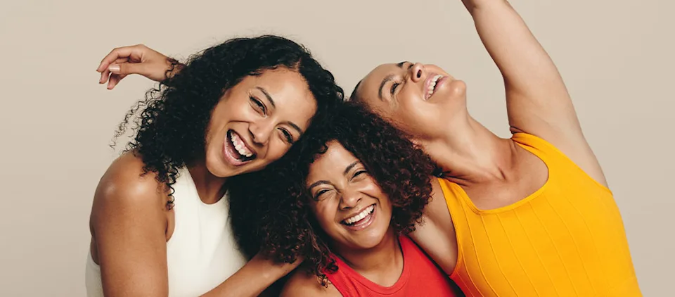 Three young women laughing happily as they stand together