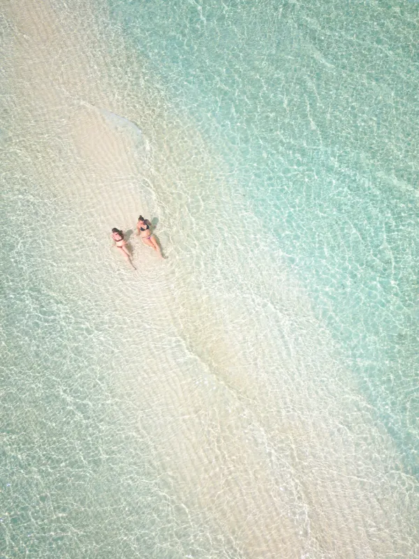 maldives-Felidhe Vaavu Atoll Island Beach Female Travellers Laying in Sea Water Drone Shot