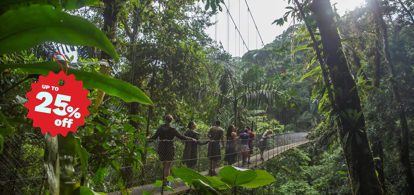 Tourists walking on a suspension bridge through lush rainforest with a red "UP TO 25% off" promotional tag in the corner.