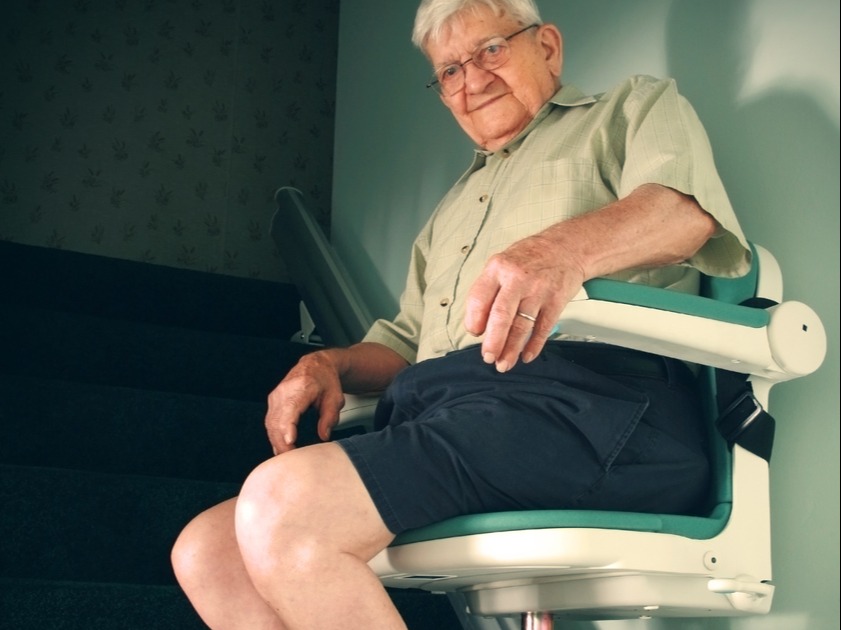 Man in shorts riding a lift up a stairway.