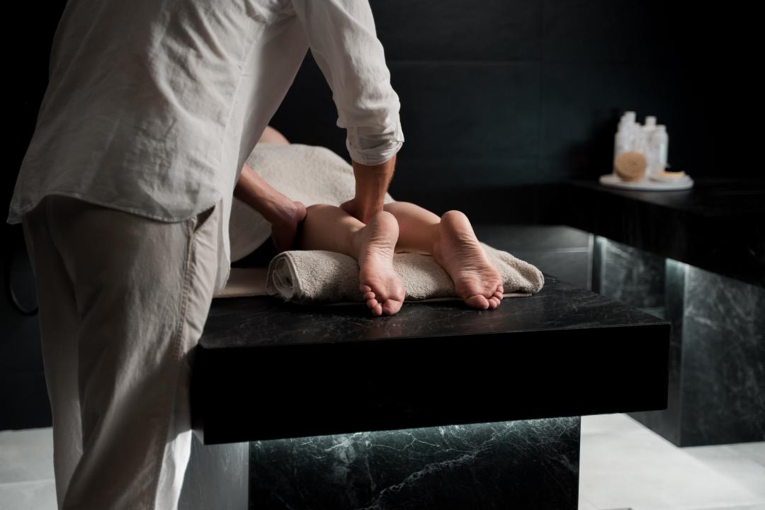 A person receiving reflexology treatment while laying on a marble table
