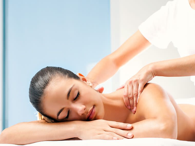 Lady appearing relaxed while receiving massage therapy on a table.