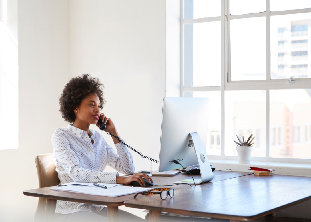 Person talking on the phone while browsing on their computer