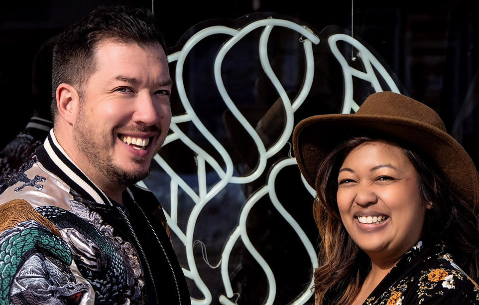 Business owners smile and pose in front of store